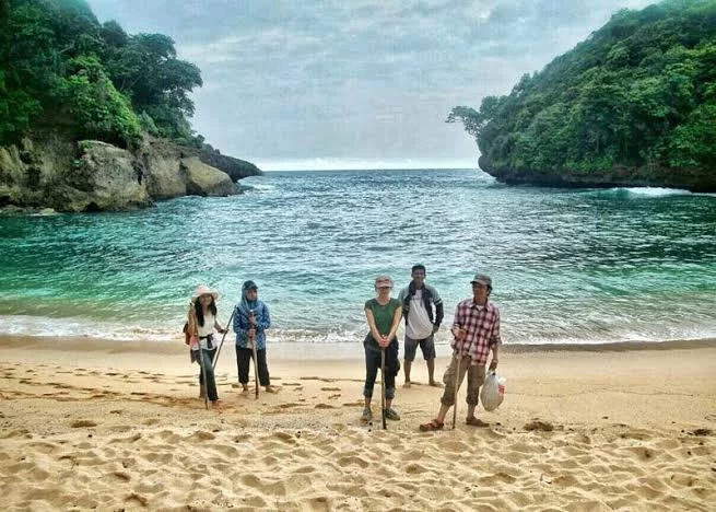 Pengunjung sedang menikmati kesegaran air saat berenang di kolam alami Teluk Bidadari yang tenang.