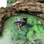 Pemandangan indah kolam alami Teluk Bidadari Malang dengan air jernih berwarna toska dikelilingi tebing karang.