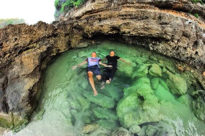 Pemandangan indah kolam alami Teluk Bidadari Malang dengan air jernih berwarna toska dikelilingi tebing karang.