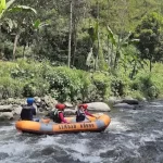 Sebuah tim sedang melakukan river tubing di sungai jernih Ledok Amprong, pilihan tempat outbound Malang yang memacu adrenalin.